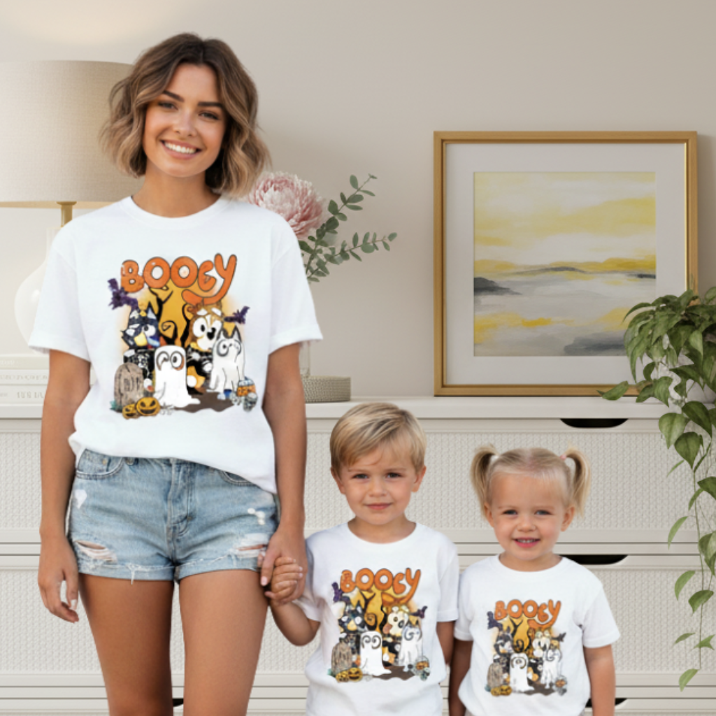 Woman and two children wearing matching 'Boogy' t-shirts with cartoon characters in a home setting.