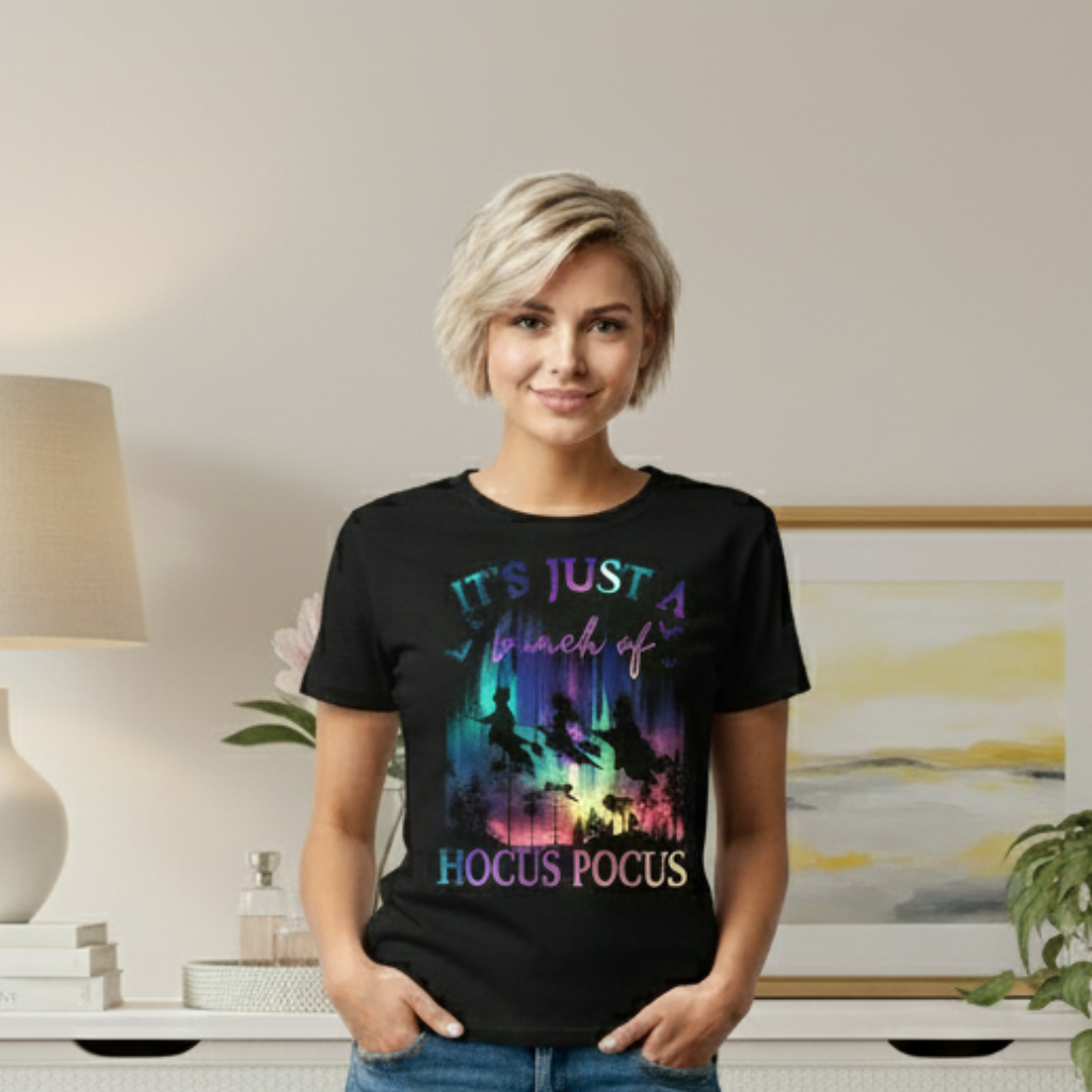 Woman wearing a black t-shirt with colorful 'Hocus Pocus' design in a room.